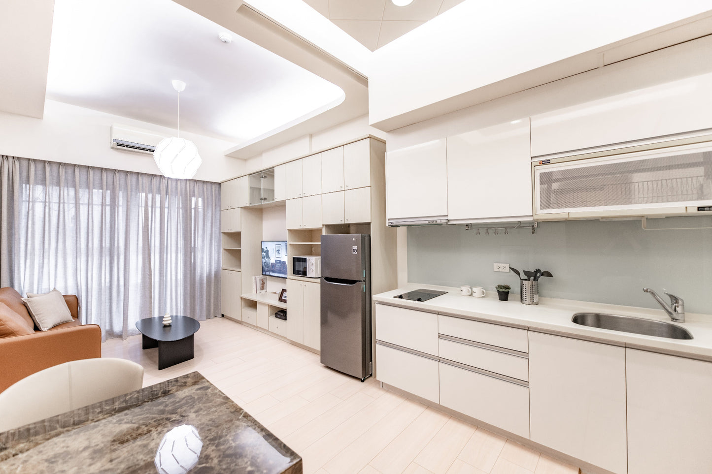 Kolette Home Serviced Apartment - Modern minimalist kitchen and living area with warm lighting in Taipei.