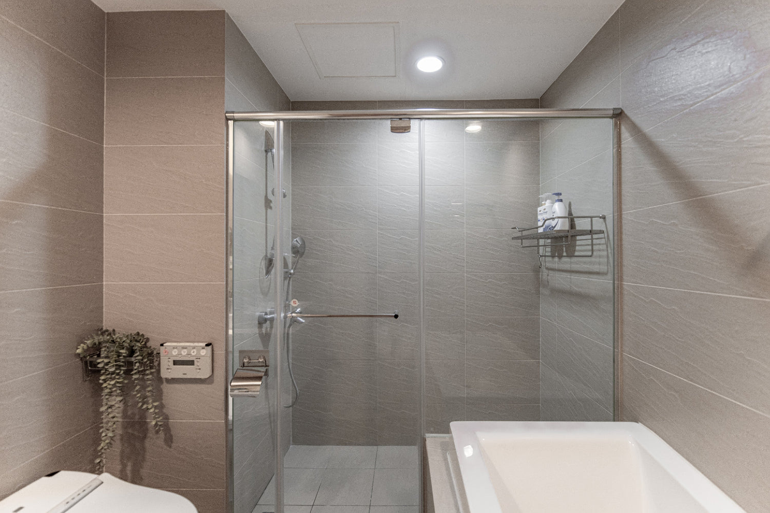 Clean hotel-grade bathroom featuring a rainfall shower/bathtub and Japanese bidet at Kolette Home apartment.